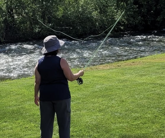 Student casting to the river on a bright summer morning